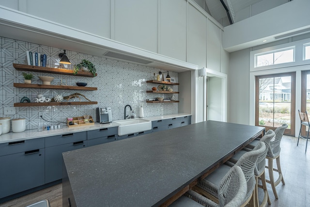bar with visible vents, decorative backsplash, a sink, and a towering ceiling
