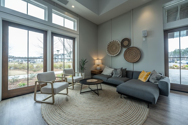 living area featuring recessed lighting, a high ceiling, wood finished floors, and a healthy amount of sunlight