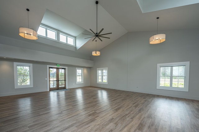 unfurnished living room with high vaulted ceiling, ceiling fan, baseboards, and wood finished floors