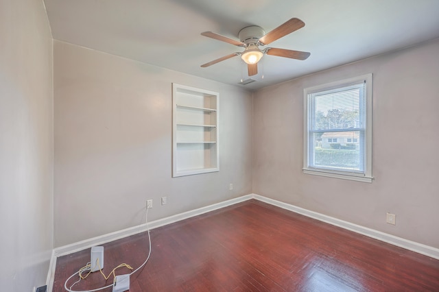 empty room featuring dark hardwood / wood-style floors, built in features, and ceiling fan