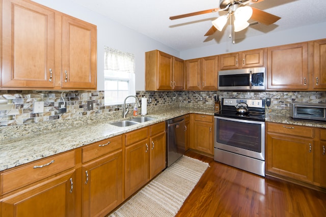 kitchen featuring light stone countertops, appliances with stainless steel finishes, backsplash, and sink