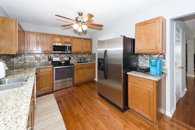 kitchen featuring sink, decorative backsplash, ceiling fan, dark hardwood / wood-style flooring, and stainless steel appliances