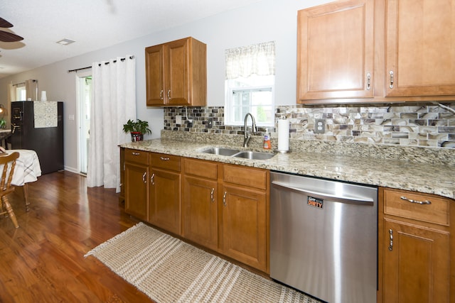 kitchen featuring light stone countertops, sink, tasteful backsplash, black fridge, and stainless steel dishwasher