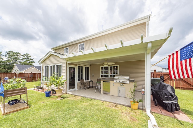 back of property with ceiling fan, a yard, a patio, and an outdoor kitchen