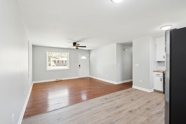 unfurnished living room featuring baseboards, visible vents, a ceiling fan, and light wood-style floors