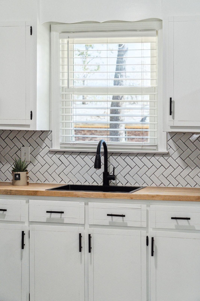 kitchen featuring white cabinetry, tasteful backsplash, a wealth of natural light, and a sink