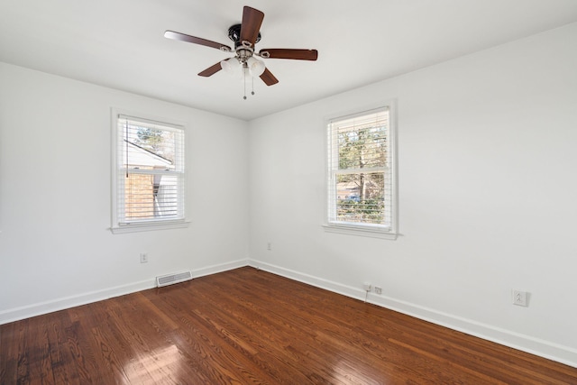 unfurnished room with dark wood-type flooring, a healthy amount of sunlight, visible vents, and baseboards