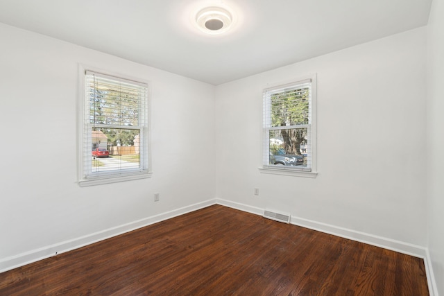 spare room with visible vents, baseboards, and dark wood-style floors