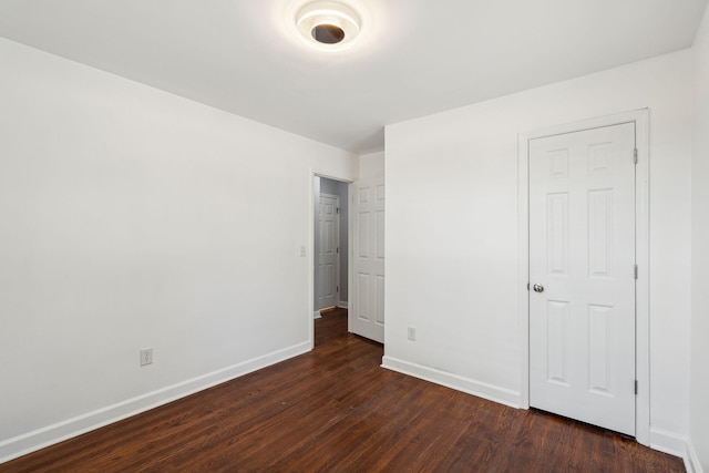 unfurnished bedroom featuring baseboards and dark wood-type flooring