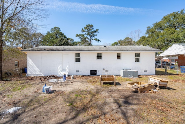 rear view of property featuring a garden, crawl space, central AC unit, and fence