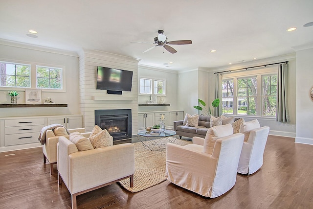 living room featuring ceiling fan, ornamental molding, dark hardwood / wood-style flooring, and a fireplace