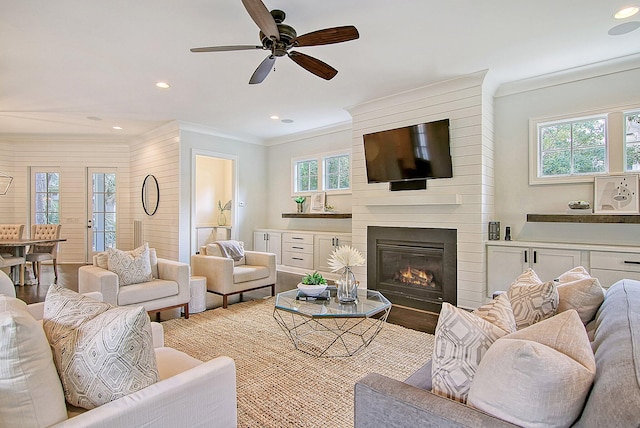 living room featuring hardwood / wood-style floors, ceiling fan, a fireplace, and ornamental molding