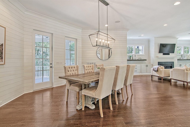 dining area featuring a wealth of natural light, a large fireplace, dark hardwood / wood-style floors, and an inviting chandelier