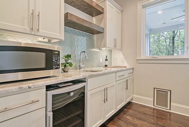 kitchen with wine cooler, light stone countertops, dark wood-type flooring, sink, and white cabinets