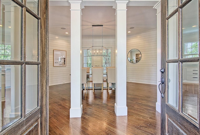 interior space featuring wood walls, wood-type flooring, an inviting chandelier, and ornate columns