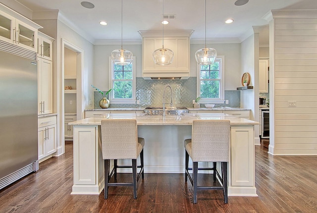 kitchen with a center island with sink, light stone counters, dark hardwood / wood-style flooring, and stainless steel built in fridge