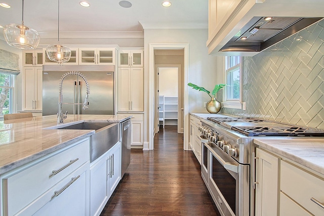 kitchen with high end appliances, a wealth of natural light, dark hardwood / wood-style floors, and custom range hood