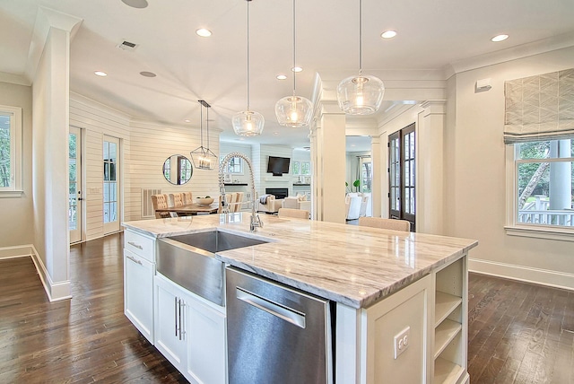 kitchen featuring a kitchen island with sink, decorative light fixtures, stainless steel dishwasher, and light stone countertops