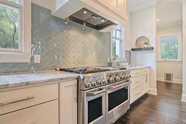 kitchen featuring crown molding, light stone countertops, premium range hood, dark hardwood / wood-style floors, and range with two ovens