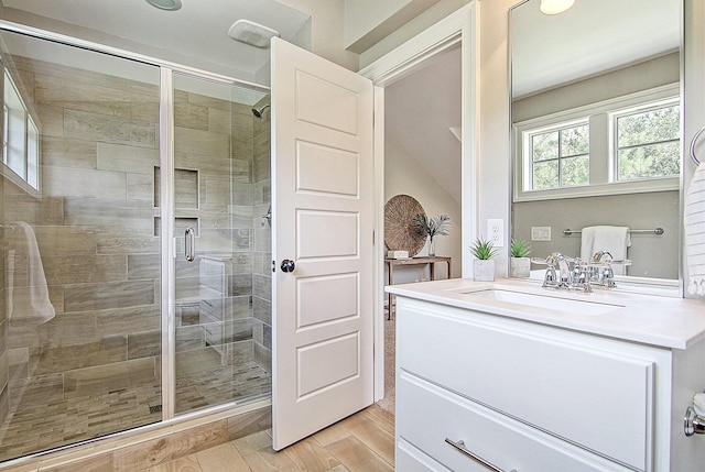 bathroom featuring a shower with door and vanity