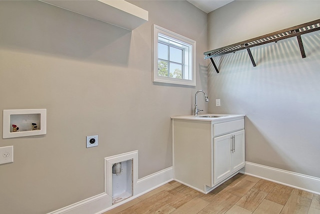 clothes washing area with hookup for a washing machine, light hardwood / wood-style floors, electric dryer hookup, sink, and cabinets