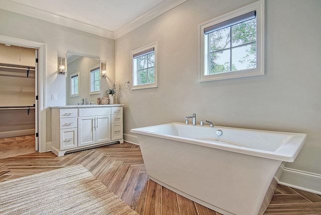 bathroom featuring a washtub, parquet flooring, crown molding, and vanity