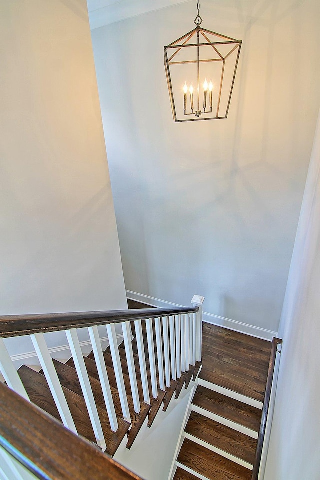 stairs featuring wood-type flooring and a chandelier