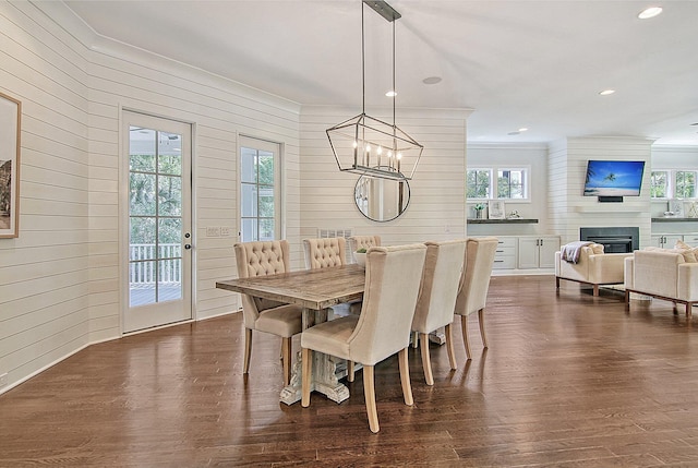 dining area featuring a wealth of natural light, a large fireplace, an inviting chandelier, and dark hardwood / wood-style flooring