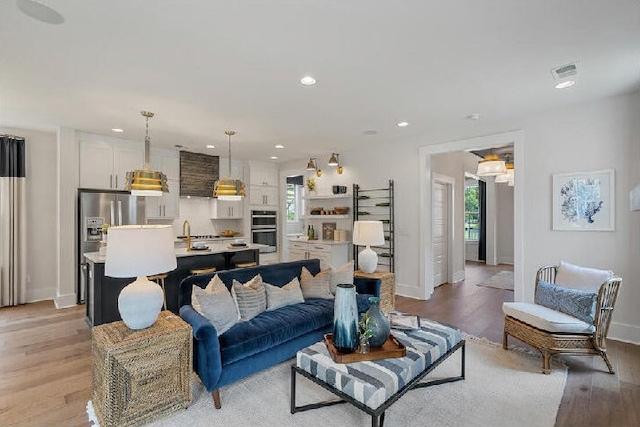 living area with recessed lighting, light wood-type flooring, and baseboards