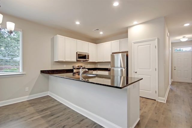 kitchen with white cabinetry, kitchen peninsula, stainless steel appliances, and light hardwood / wood-style floors