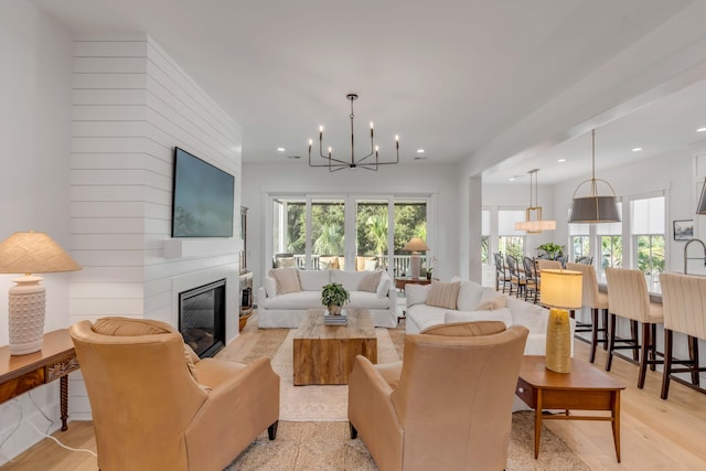 living room with a large fireplace, a notable chandelier, and light hardwood / wood-style flooring