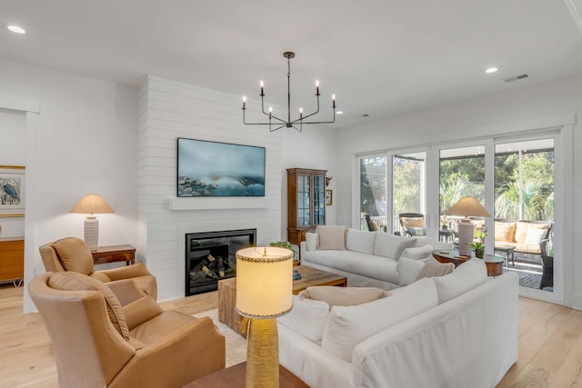 living room with a fireplace, a chandelier, and light wood-type flooring