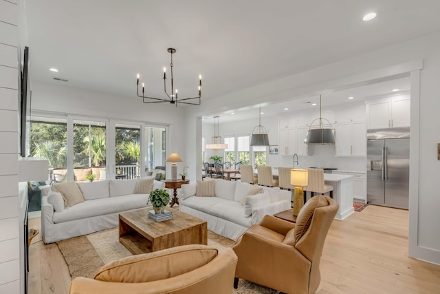 living room featuring sink, a chandelier, and light hardwood / wood-style flooring