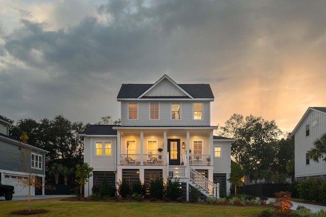 view of front facade with covered porch, a garage, and a lawn