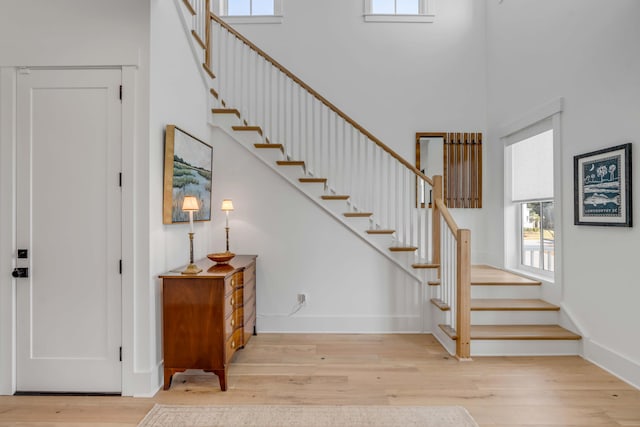 stairway with hardwood / wood-style flooring and a towering ceiling