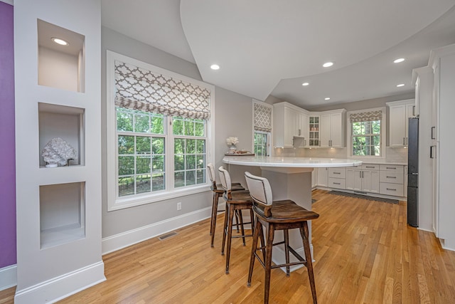 kitchen featuring freestanding refrigerator, light wood-style flooring, a breakfast bar area, white cabinets, and recessed lighting