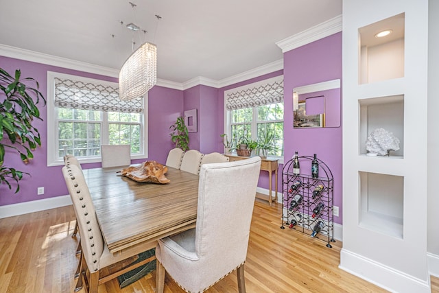 dining space featuring light wood-style floors, baseboards, crown molding, and healthy amount of natural light