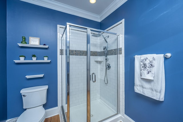 bathroom with a stall shower, ornamental molding, toilet, and baseboards