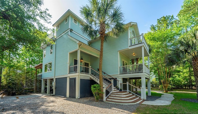 rear view of property with stairway, a balcony, and covered porch