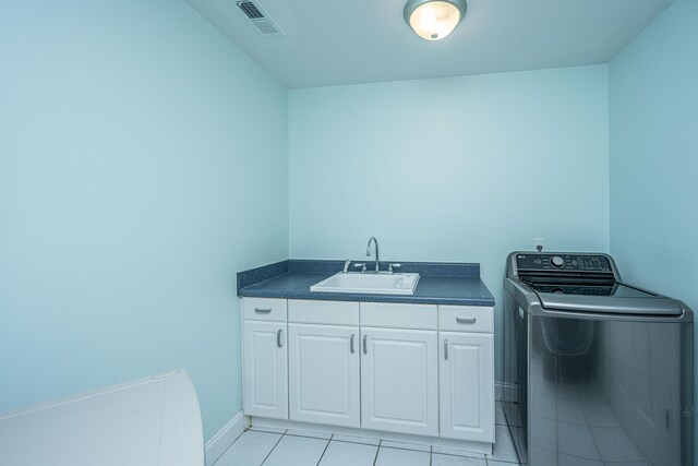 clothes washing area with washer / dryer, cabinet space, light tile patterned floors, and baseboards