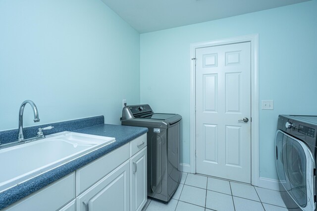 laundry area featuring washing machine and clothes dryer, cabinet space, and light tile patterned floors