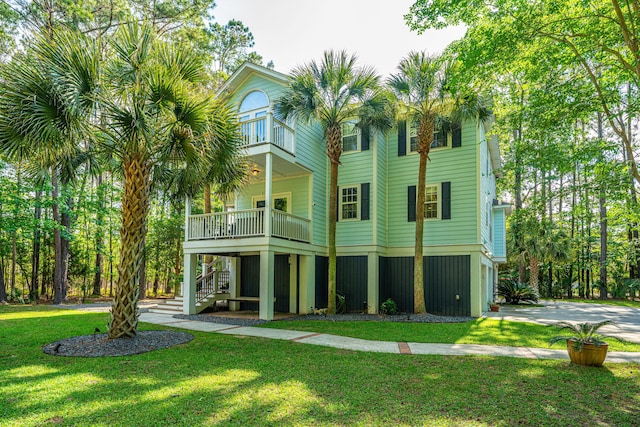 back of house with a balcony, stairway, a lawn, and an attached garage