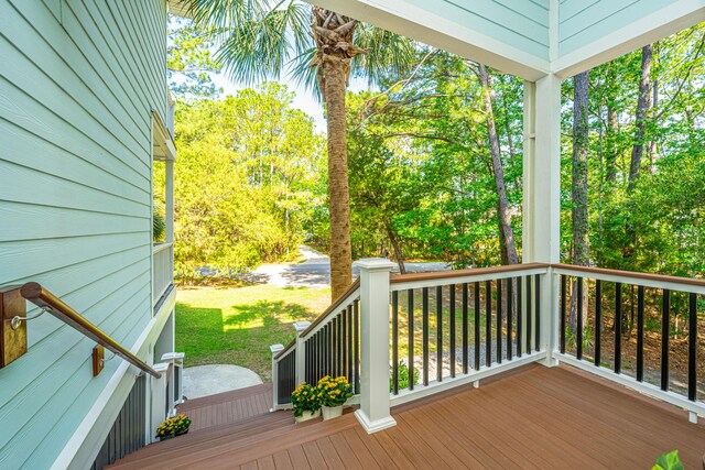 wooden terrace with a lawn, covered porch, and view of wooded area