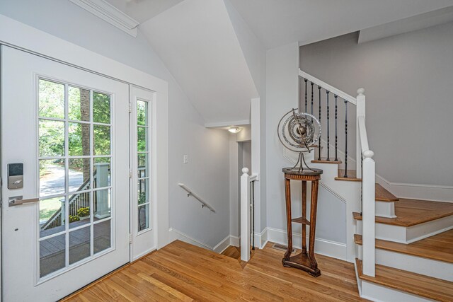 staircase with wood finished floors, baseboards, and vaulted ceiling