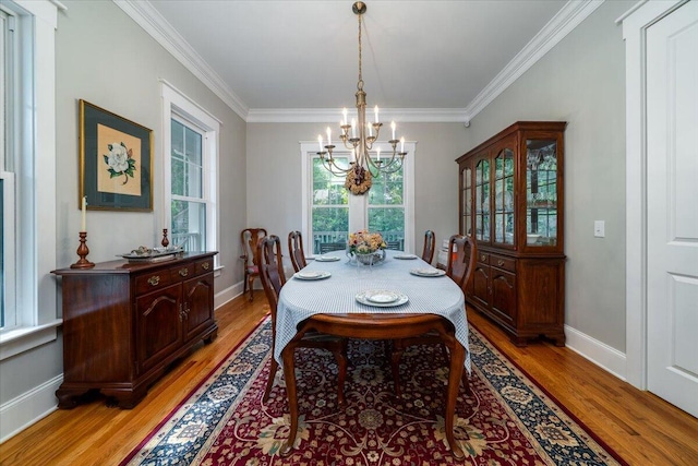 dining room with an inviting chandelier, ornamental molding, and light wood-style flooring
