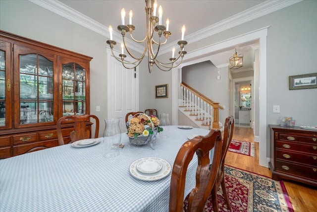 dining area featuring an inviting chandelier, ornamental molding, and light wood-type flooring