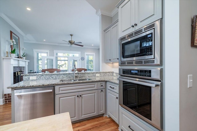 kitchen featuring crown molding, a sink, light wood-type flooring, and stainless steel appliances