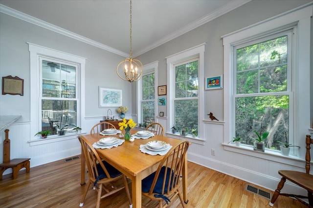 dining space with crown molding, a chandelier, visible vents, and light wood-style floors