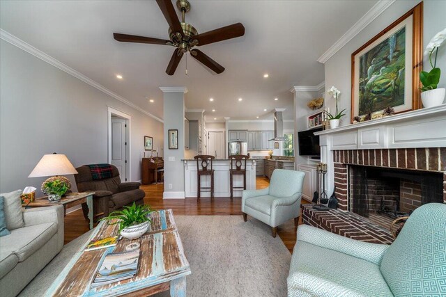 living area with a brick fireplace, recessed lighting, ceiling fan, and wood finished floors