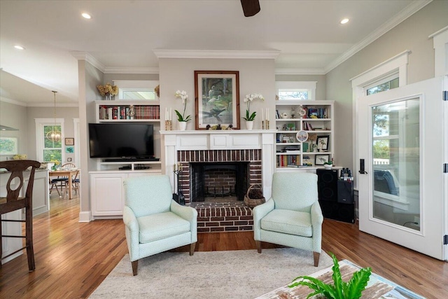 living area with ornamental molding, a fireplace, recessed lighting, and wood finished floors